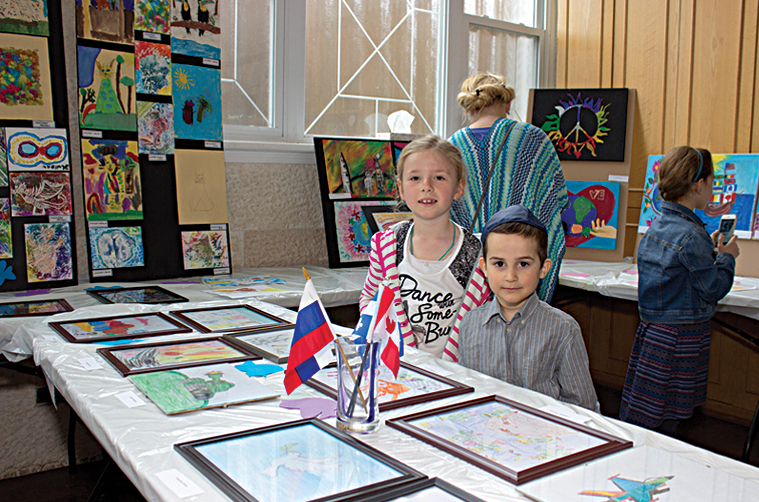 Children displaying their paintings at an art exhibition