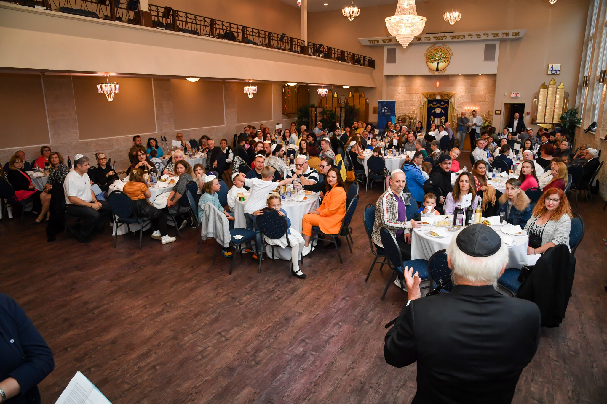 Large community banquet dinner event inside the synagogue hall